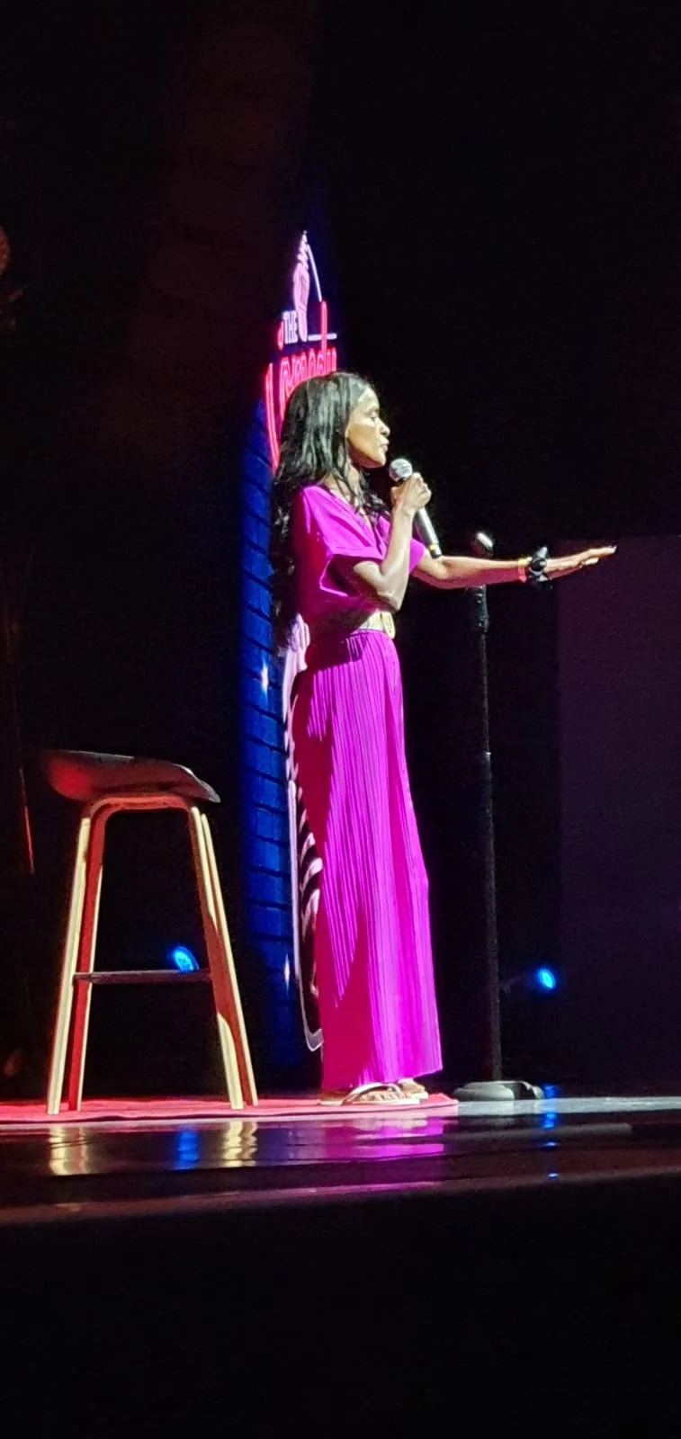 Sahar Ali speaking on stage in a bright pink dress